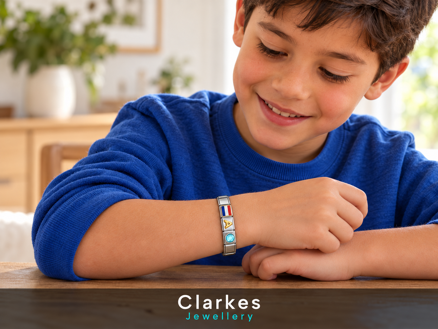 A boy in blue wearing a personalised silver bracelet with a flag, initial and birthstone